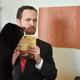 A man reading the Frasier cookbook, impeded by his cat
